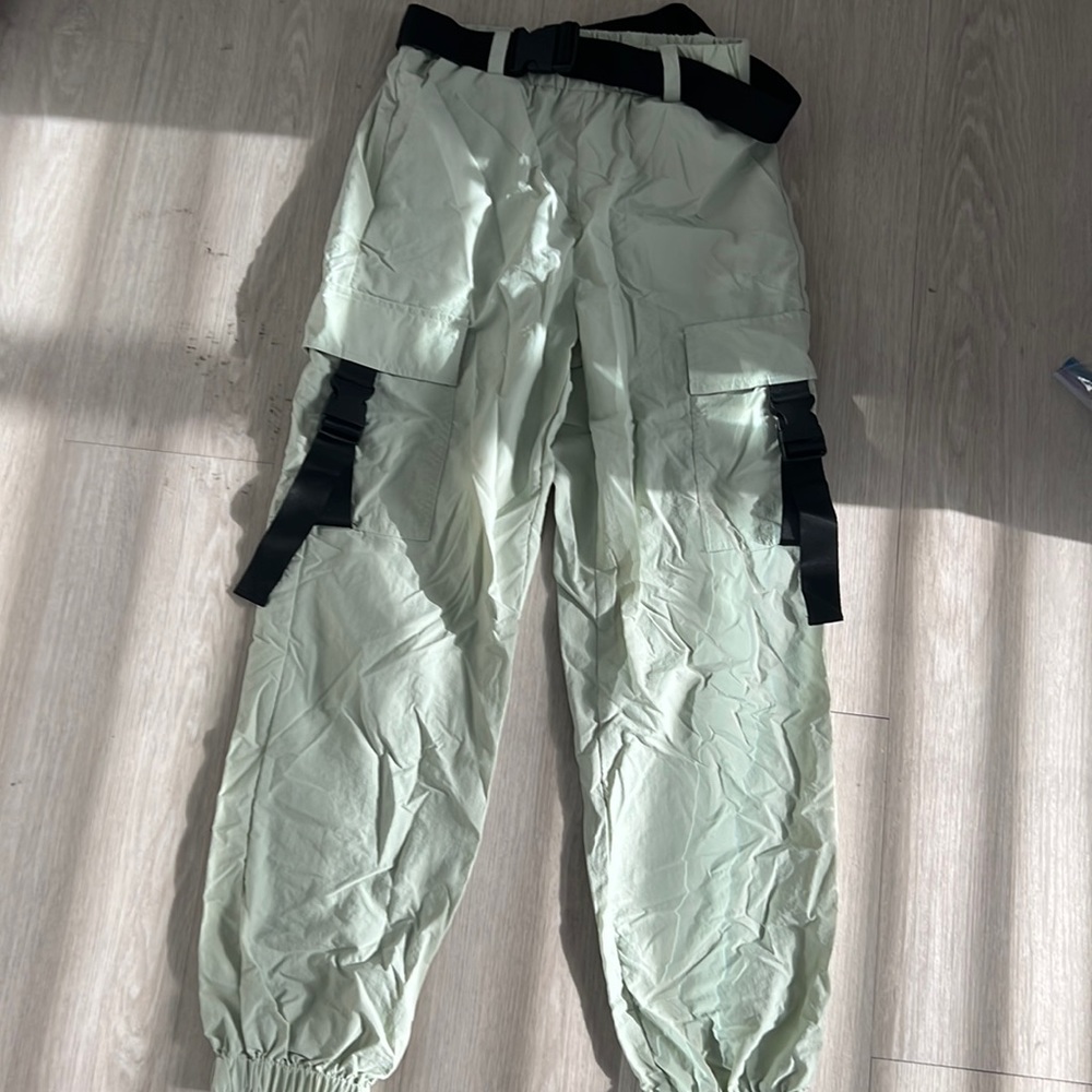 Pants the color green with a black belt around it
